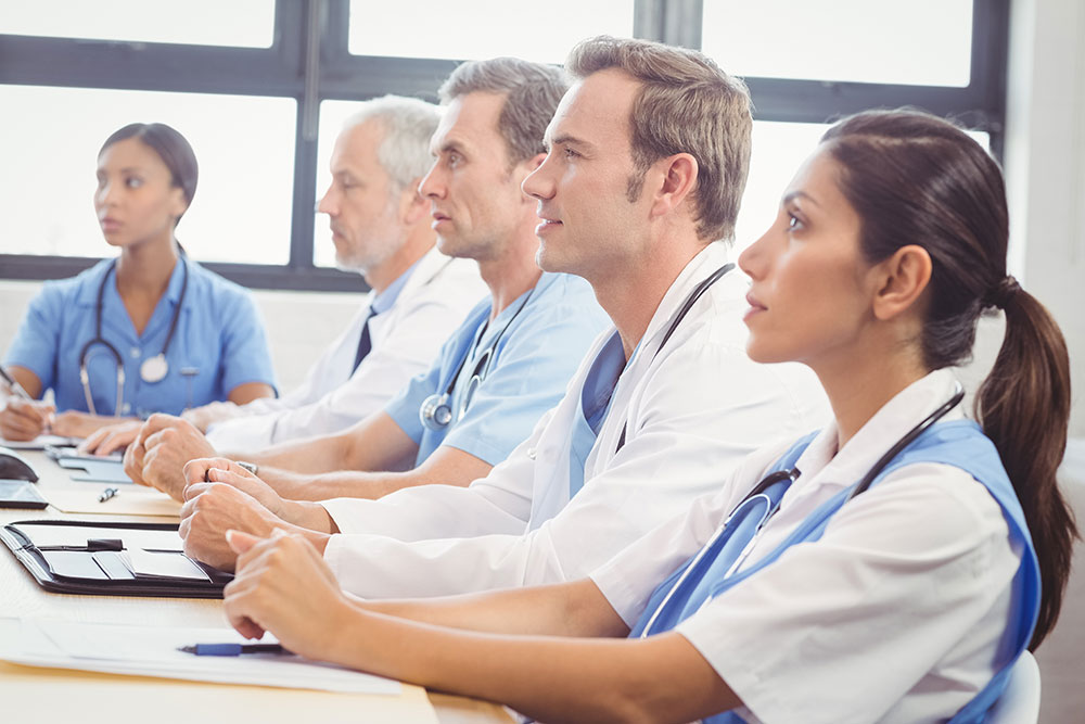 Group of five younger and older doctors and nurses, men and women, seated and paying attention at a continuing medical education class