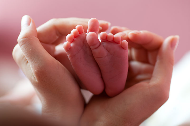 Tiny newborn baby's feet cupped in mother's hands