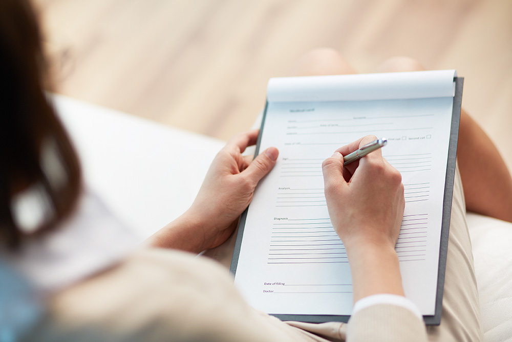 Woman seated filling out a form on a clipboard