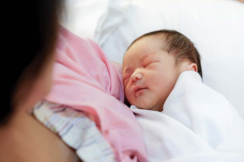 Peaceful, wrapped up, sleeping new-born baby in mother's arms