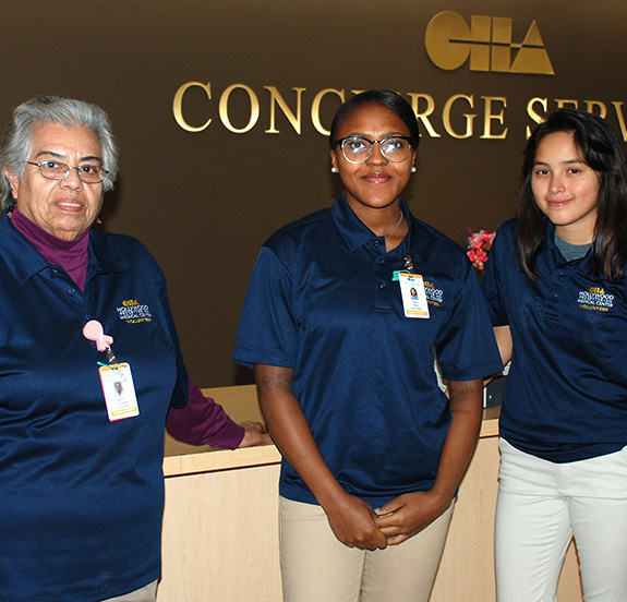 Three volunteers, one older woman and two younger women, at a hospital event
