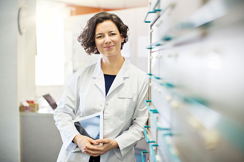 Woman doctor with wavy brown short hair, standing next to file cabinets in an office