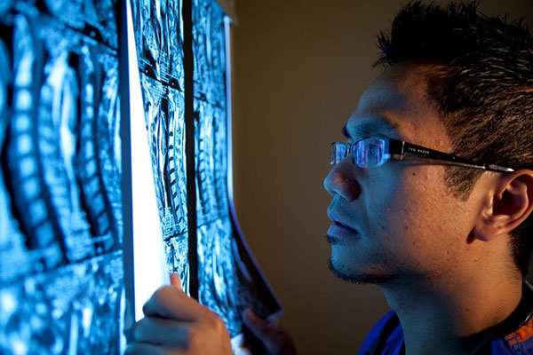 Asian doctor closely examining X-Rays