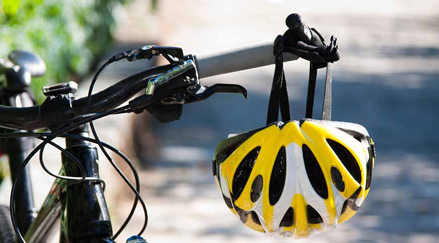 Bike handlebars with a yellow helmet hanging off of them